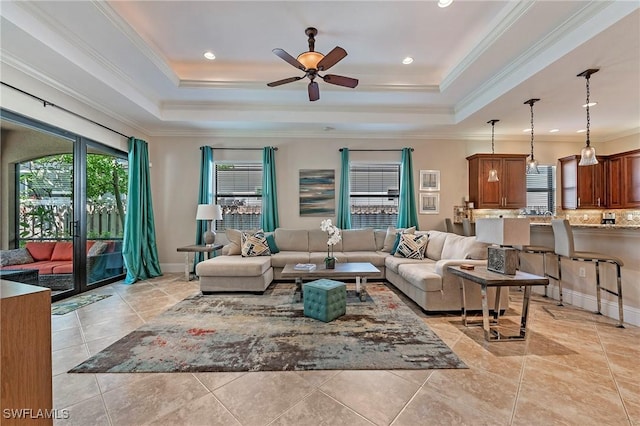 tiled living room featuring a raised ceiling, ornamental molding, and ceiling fan