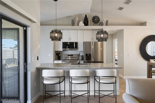 kitchen with stainless steel appliances, light stone countertops, white cabinets, and decorative light fixtures