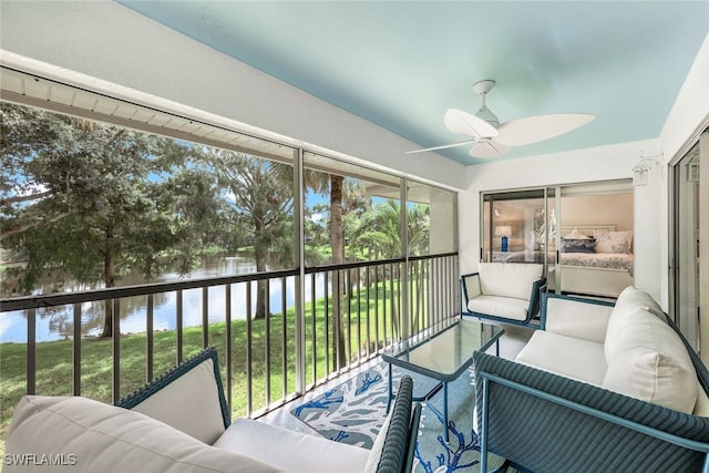 sunroom / solarium with ceiling fan and a water view