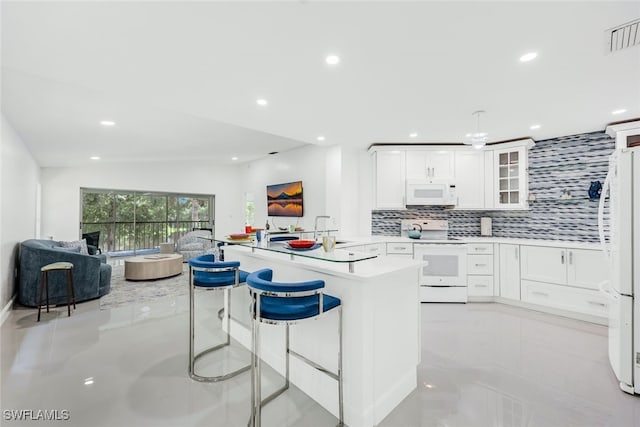 kitchen featuring glass insert cabinets, open floor plan, a sink, white appliances, and a peninsula