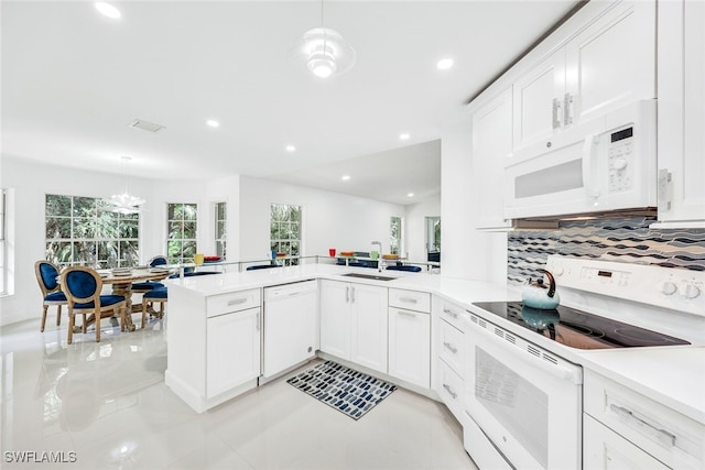 kitchen with white cabinetry, hanging light fixtures, kitchen peninsula, white appliances, and decorative backsplash