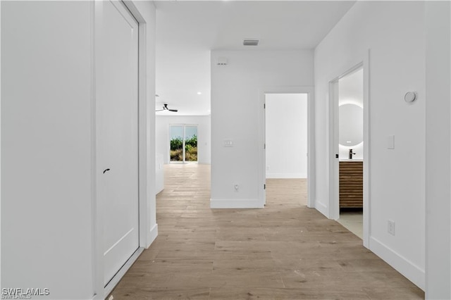 corridor with light hardwood / wood-style floors and sink