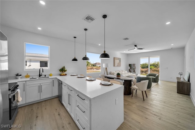 kitchen with sink, stove, white cabinets, stainless steel dishwasher, and kitchen peninsula