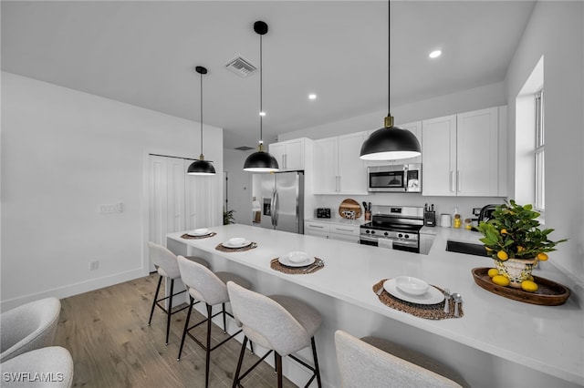 kitchen with sink, a breakfast bar area, appliances with stainless steel finishes, white cabinets, and kitchen peninsula