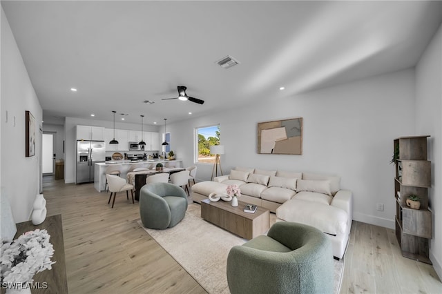 living room with ceiling fan and light hardwood / wood-style floors