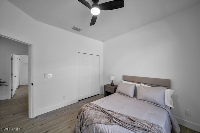 bedroom with dark wood-type flooring, a closet, and ceiling fan