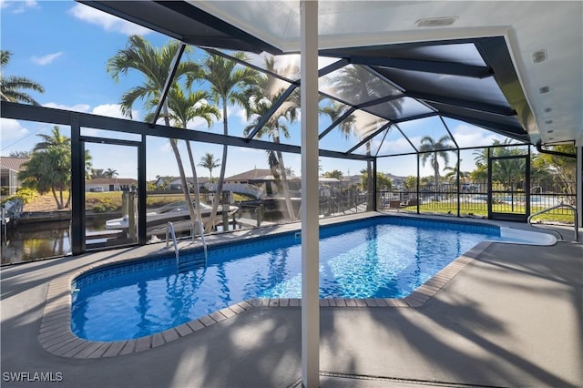 view of swimming pool with a lanai, a patio area, and a water view