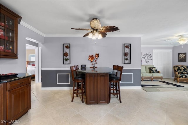 tiled dining space with crown molding and ceiling fan