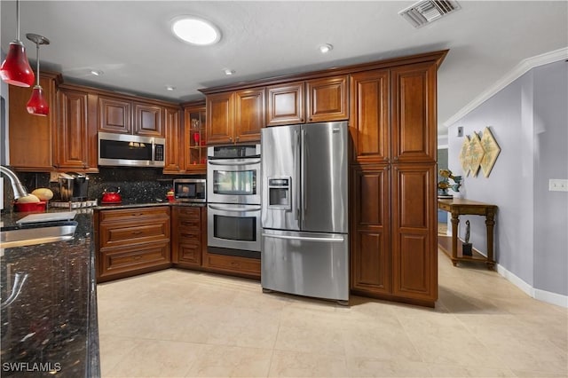 kitchen featuring sink, dark stone counters, hanging light fixtures, ornamental molding, and stainless steel appliances