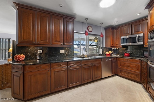 kitchen featuring appliances with stainless steel finishes, sink, decorative backsplash, hanging light fixtures, and dark stone counters