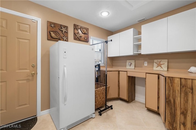 kitchen with white cabinetry, light tile patterned floors, and white refrigerator