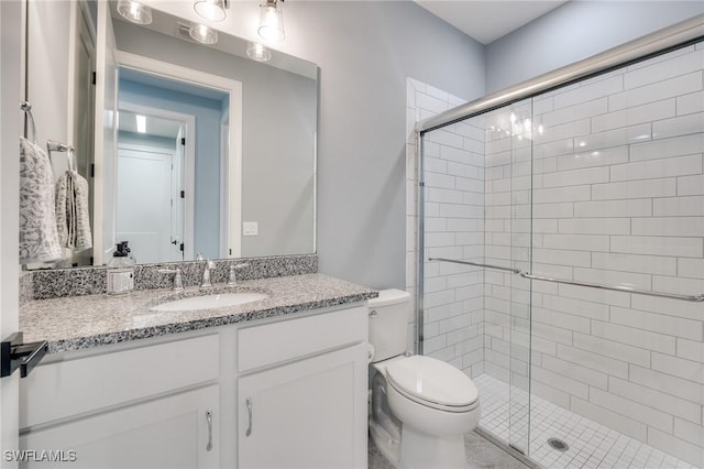 bathroom with vanity, toilet, and a shower with shower door