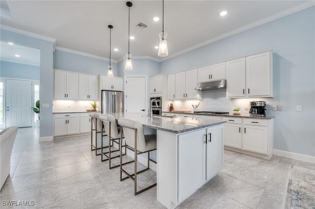 kitchen with decorative light fixtures, white cabinetry, dark stone countertops, a kitchen island with sink, and stainless steel appliances