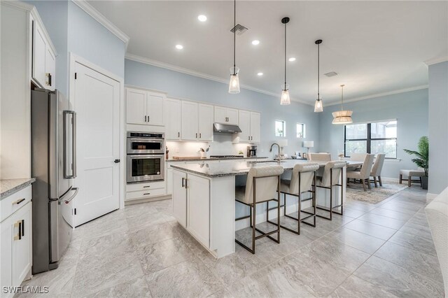 kitchen with a kitchen island with sink, light stone counters, stainless steel appliances, and white cabinetry