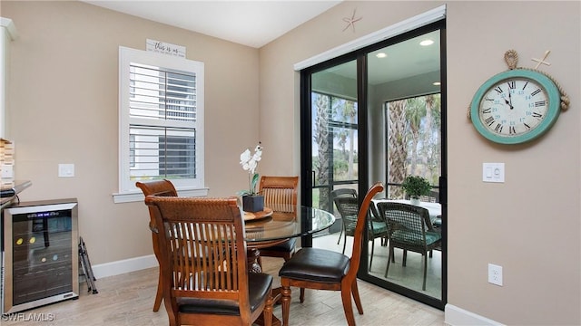 dining space with light wood-type flooring and beverage cooler