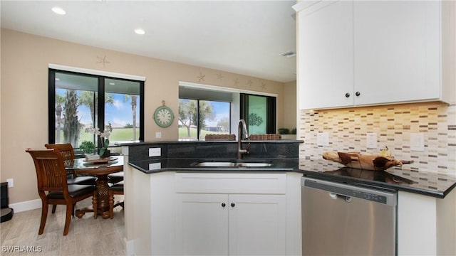 kitchen with dishwasher, white cabinetry, sink, dark stone countertops, and backsplash