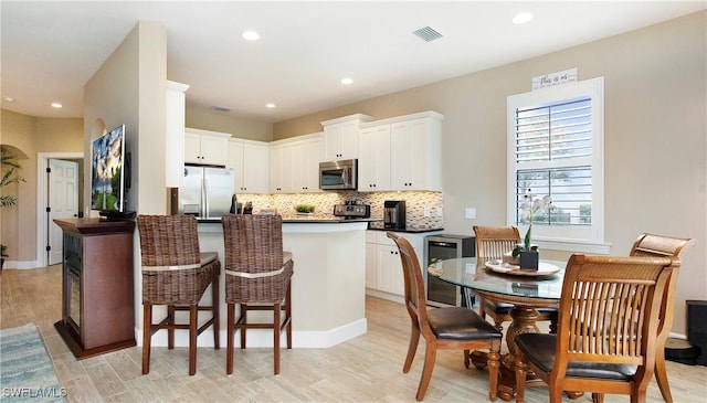 kitchen featuring white cabinets, tasteful backsplash, a kitchen island, light hardwood / wood-style floors, and stainless steel appliances