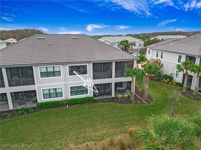 rear view of property with a sunroom and a lawn