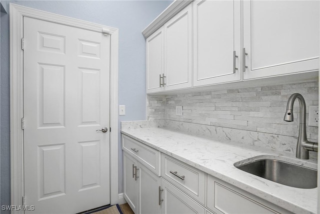 kitchen featuring white cabinetry, sink, decorative backsplash, and light stone countertops