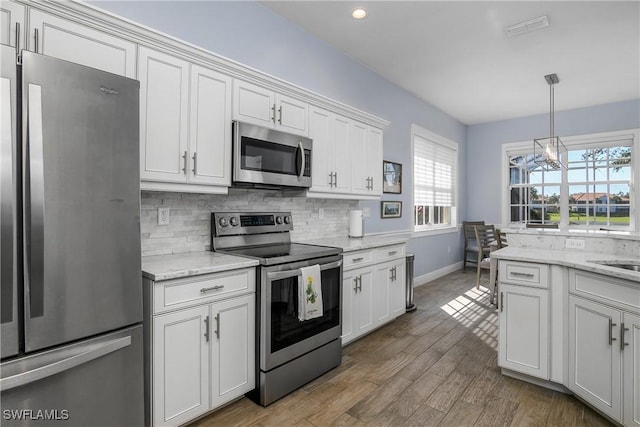 kitchen with tasteful backsplash, light stone countertops, stainless steel appliances, and white cabinets