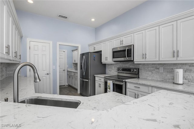 kitchen featuring white cabinetry, appliances with stainless steel finishes, sink, and light stone counters