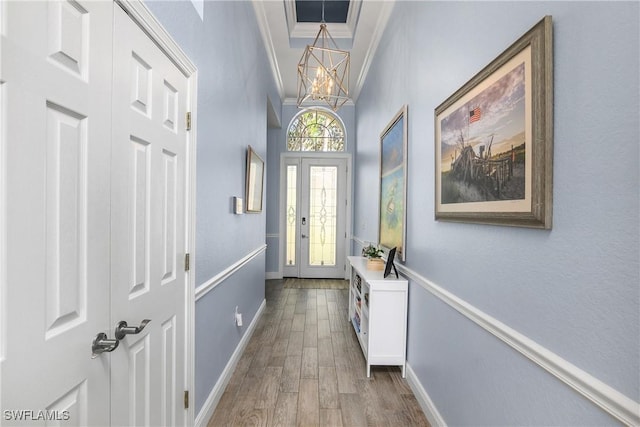 doorway with crown molding, a towering ceiling, hardwood / wood-style floors, and a chandelier