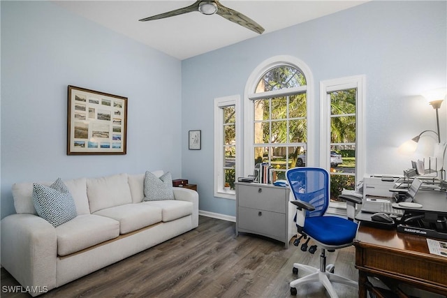 home office featuring ceiling fan, a wealth of natural light, and dark hardwood / wood-style flooring