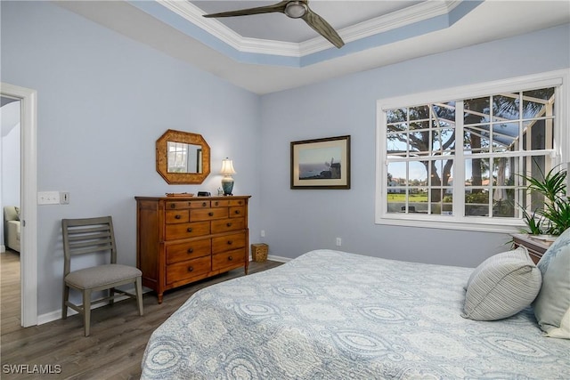 bedroom with ornamental molding, dark wood-type flooring, ceiling fan, and a tray ceiling