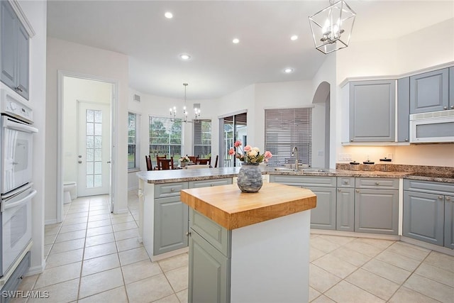 kitchen with white appliances, a center island, hanging light fixtures, gray cabinets, and a chandelier