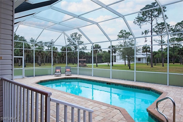 view of pool with glass enclosure, a patio area, and a lawn