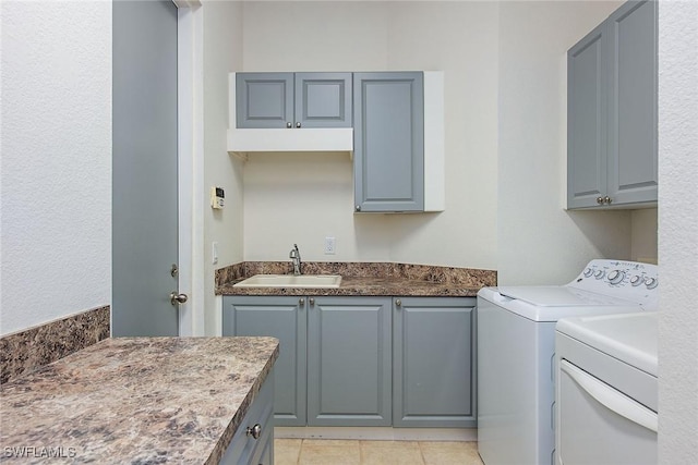 washroom with sink, light tile patterned floors, cabinets, and independent washer and dryer