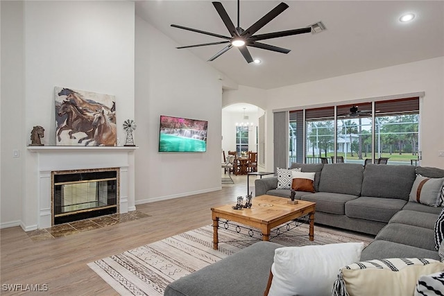 living room featuring light hardwood / wood-style floors, ceiling fan with notable chandelier, and high vaulted ceiling