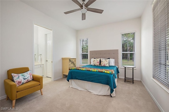 bedroom featuring ceiling fan, light colored carpet, and ensuite bathroom