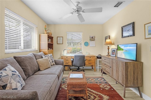 home office featuring light wood-type flooring, ceiling fan, and a wealth of natural light