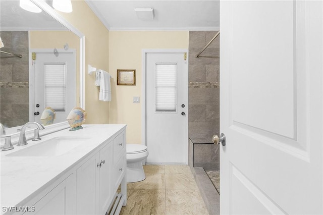 bathroom featuring tile patterned flooring, vanity, toilet, ornamental molding, and tiled shower