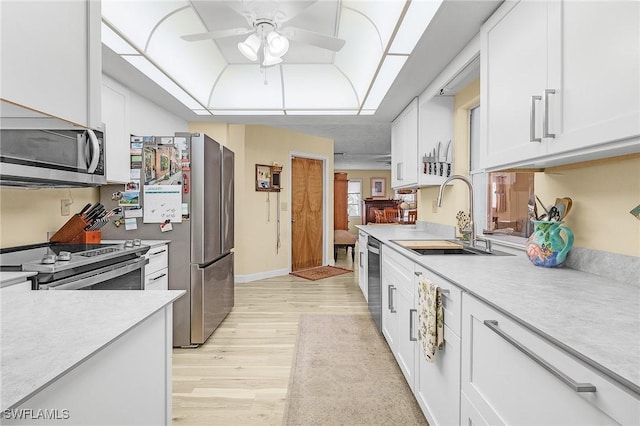 kitchen with ceiling fan, sink, white cabinets, light wood-type flooring, and stainless steel appliances