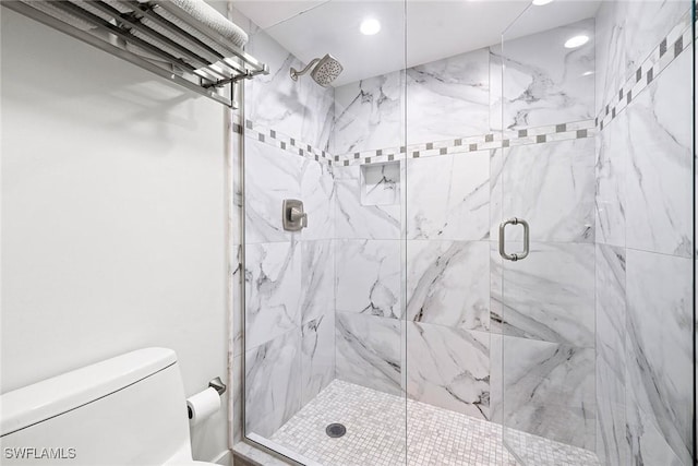 bathroom featuring a shower with door and toilet