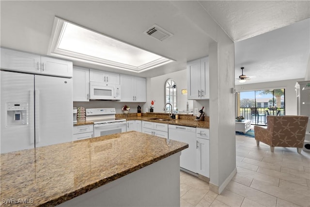 kitchen with sink, white appliances, white cabinets, kitchen peninsula, and dark stone counters