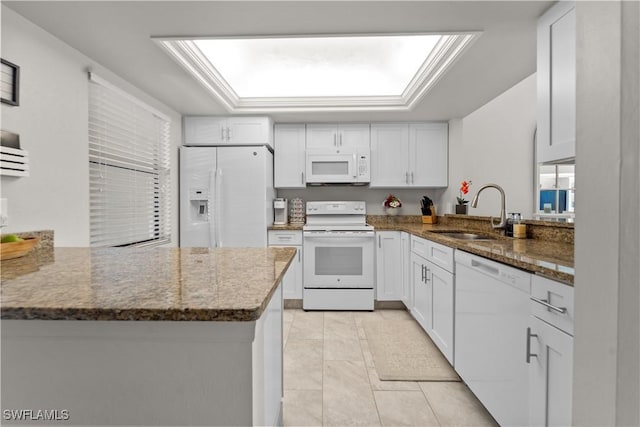 kitchen featuring sink, white cabinets, dark stone counters, kitchen peninsula, and white appliances