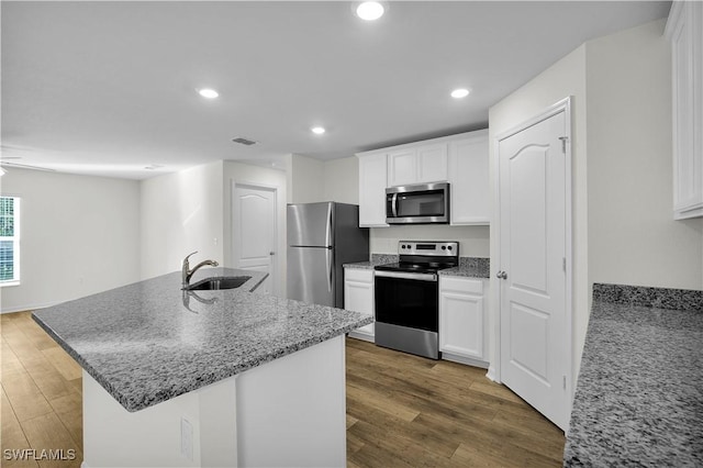 kitchen featuring sink, stainless steel appliances, white cabinetry, and an island with sink