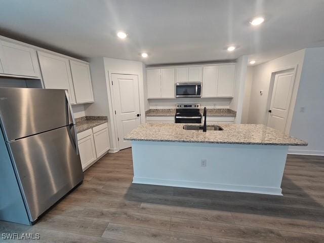 723 Brannen Ave, Lehigh Acres, FL 33974 - kitchen with stainless steel appliances, white cabinetry, a sink, dark wood-type flooring, and light stone countertops