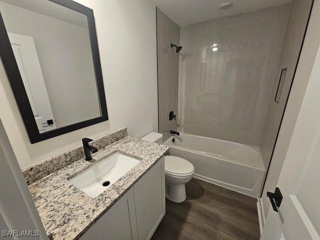 723 Brannen Ave, Lehigh Acres, FL 33974 - bathroom with wood finished floors, toilet, vanity, and shower / bath combination
