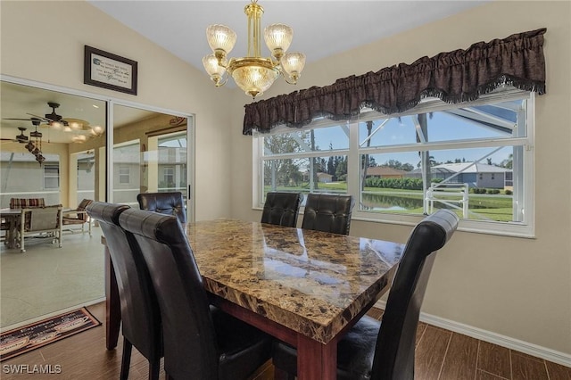 dining room featuring ceiling fan with notable chandelier, a water view, and vaulted ceiling