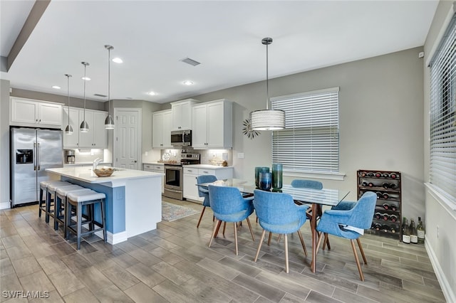 kitchen featuring pendant lighting, a kitchen island, white cabinets, and appliances with stainless steel finishes