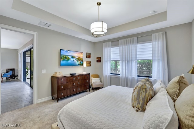 bedroom with a tray ceiling, light carpet, and access to outside