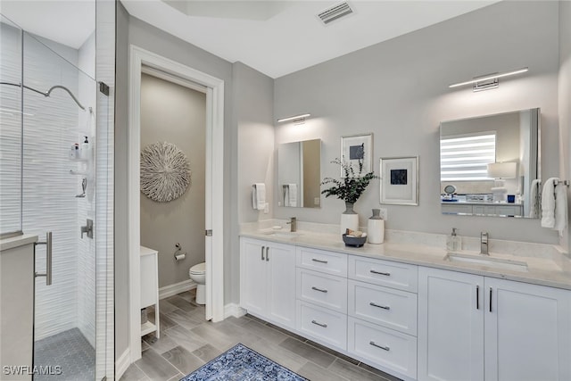 bathroom with a shower with door, vanity, and toilet