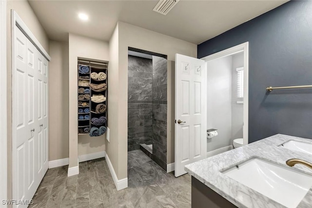 bathroom with vanity, a tile shower, and toilet