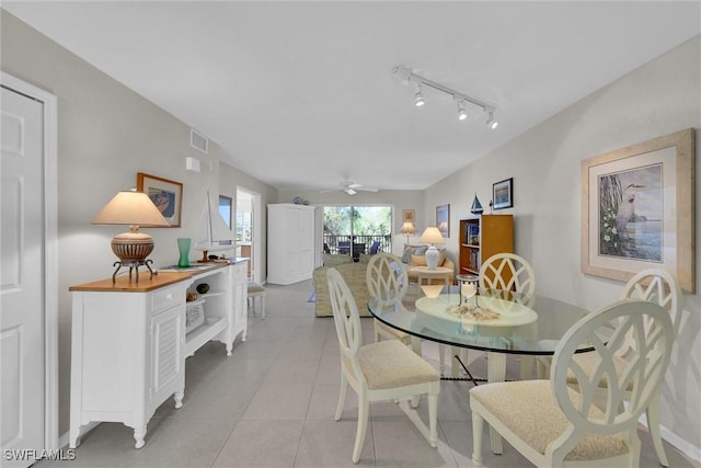 tiled dining room featuring track lighting and ceiling fan