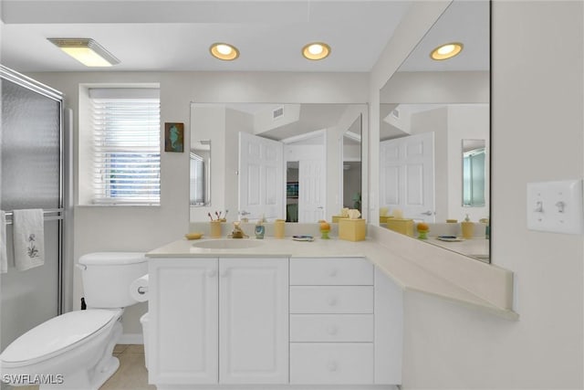 bathroom with a shower with door, vanity, tile patterned floors, and toilet