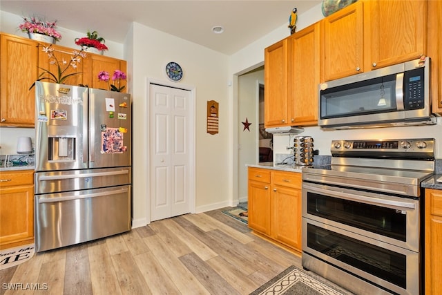 kitchen featuring appliances with stainless steel finishes and light hardwood / wood-style flooring